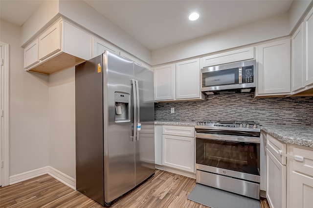 kitchen featuring white cabinets, light stone counters, stainless steel appliances, and light hardwood / wood-style flooring