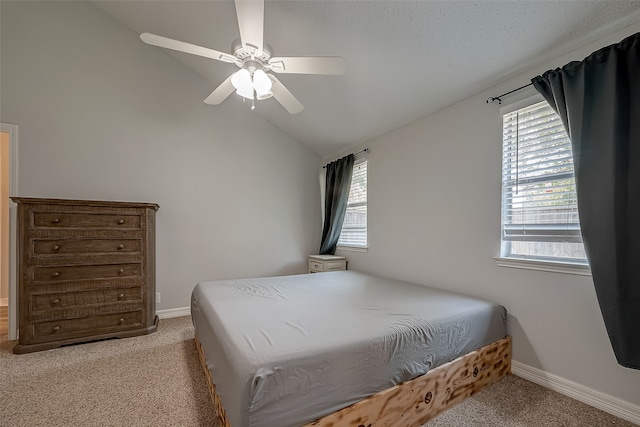 carpeted bedroom featuring a textured ceiling, ceiling fan, vaulted ceiling, and multiple windows