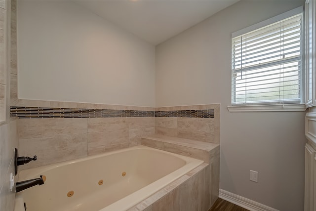 bathroom with lofted ceiling and tiled tub