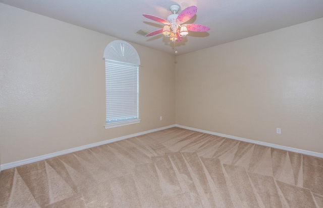 carpeted empty room with visible vents, a ceiling fan, and baseboards