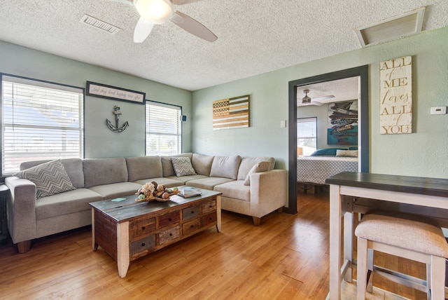 living room featuring a textured ceiling, light hardwood / wood-style flooring, and ceiling fan