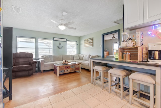 living room featuring a textured ceiling, a wealth of natural light, ceiling fan, and light hardwood / wood-style floors