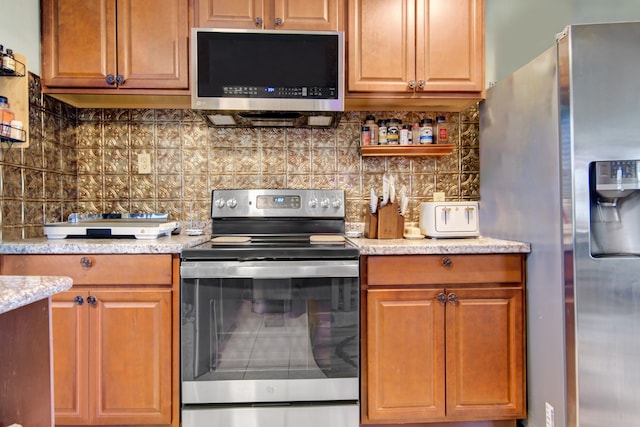 kitchen featuring backsplash, stainless steel appliances, and light stone countertops