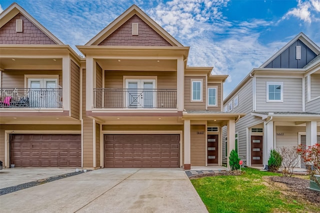 townhome / multi-family property featuring a garage, concrete driveway, a balcony, and french doors