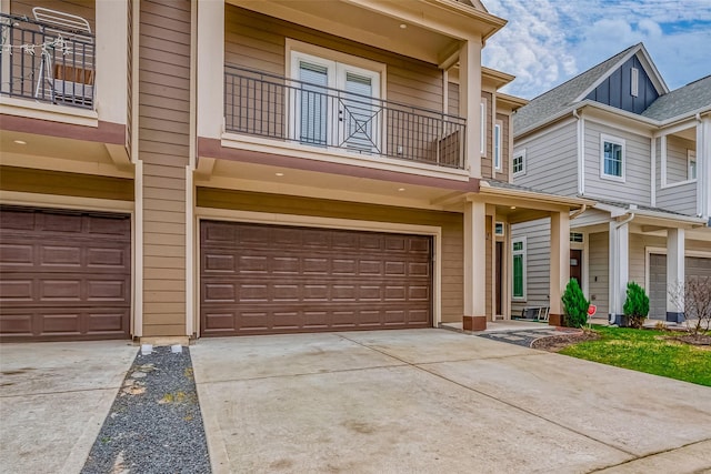 view of front of home featuring driveway, an attached garage, and a balcony