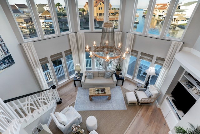 living room featuring a towering ceiling, wood-type flooring, and an inviting chandelier