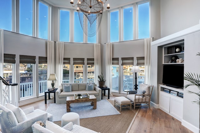 living room featuring light hardwood / wood-style floors, a high ceiling, and a chandelier