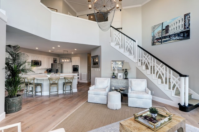 living room with ornamental molding, a high ceiling, and light hardwood / wood-style flooring