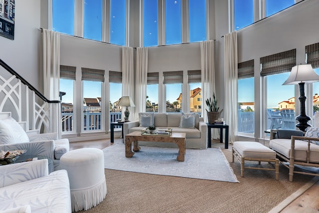 living room with a wealth of natural light, a towering ceiling, and wood-type flooring