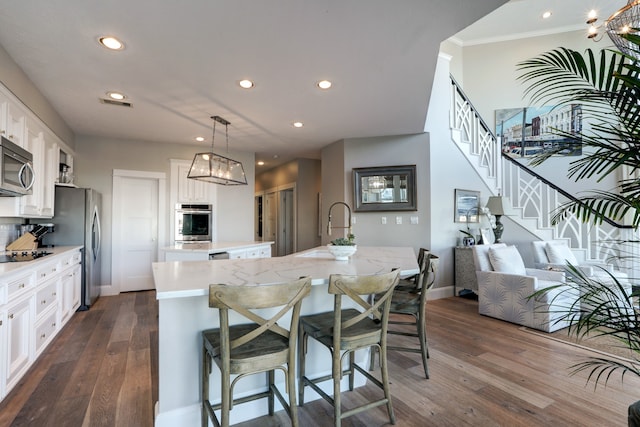 kitchen with a large island, white cabinetry, stainless steel appliances, and a breakfast bar