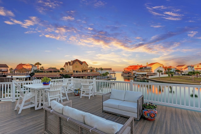 deck at dusk featuring an outdoor living space and a water view