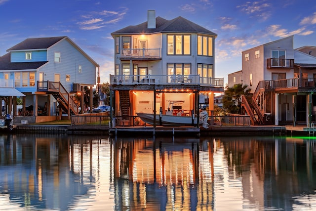 back house at dusk with a balcony and a water view