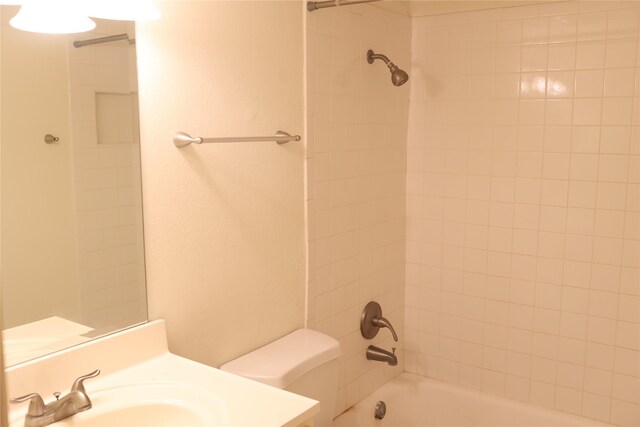 full bathroom featuring tiled shower / bath, vanity, and toilet