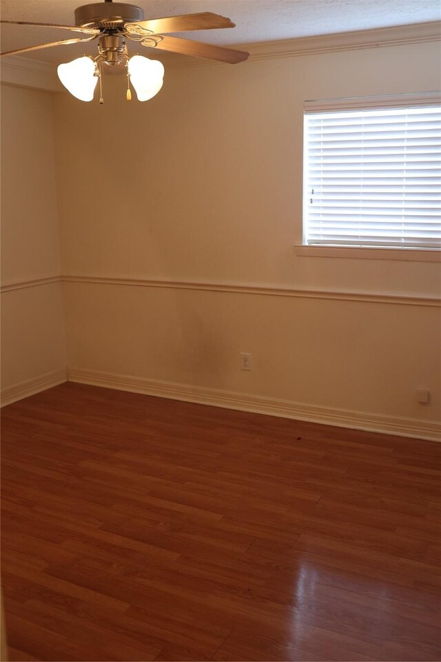 spare room featuring crown molding, dark wood-type flooring, and ceiling fan