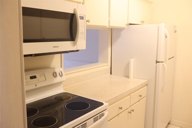 kitchen featuring white cabinetry and white appliances