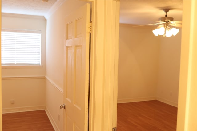 corridor featuring a textured ceiling, crown molding, and hardwood / wood-style flooring