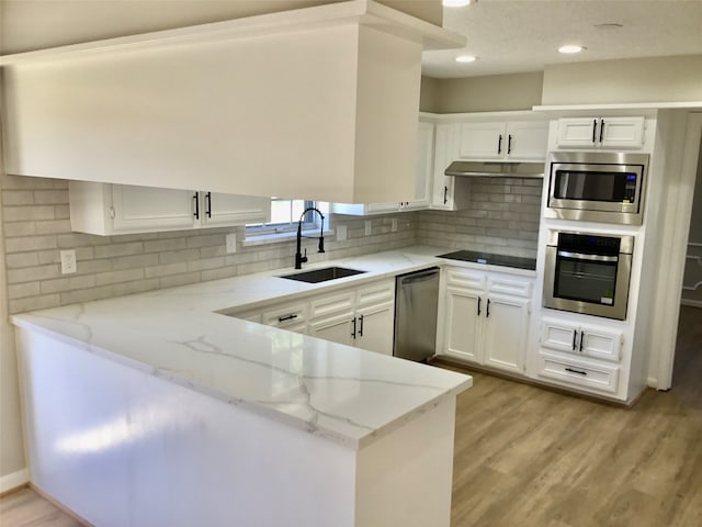 kitchen featuring light wood-type flooring, light stone counters, stainless steel appliances, white cabinetry, and sink