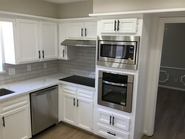 kitchen with light stone counters, appliances with stainless steel finishes, white cabinets, and decorative backsplash