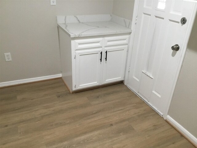 interior space with white cabinetry, light stone countertops, and light hardwood / wood-style floors