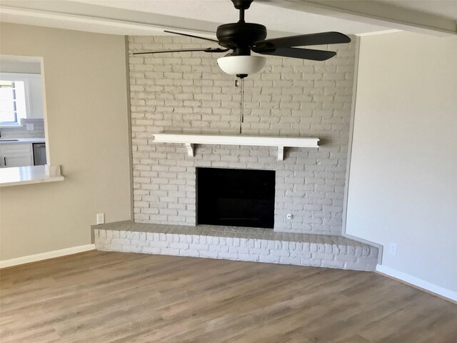 room details featuring a fireplace, dishwasher, hardwood / wood-style floors, sink, and ceiling fan