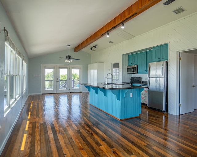 kitchen with track lighting, stainless steel appliances, a kitchen breakfast bar, dark hardwood / wood-style flooring, and vaulted ceiling with beams