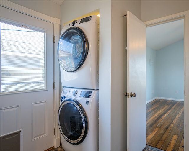 laundry room featuring dark wood-type flooring, a wealth of natural light, and stacked washer / drying machine