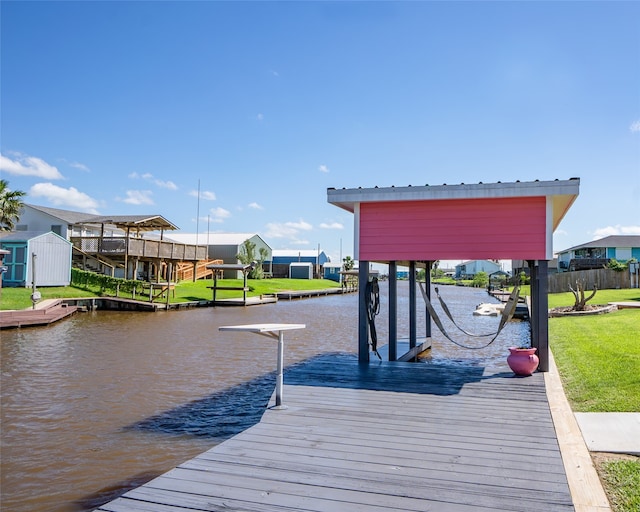 view of dock with a water view and a lawn