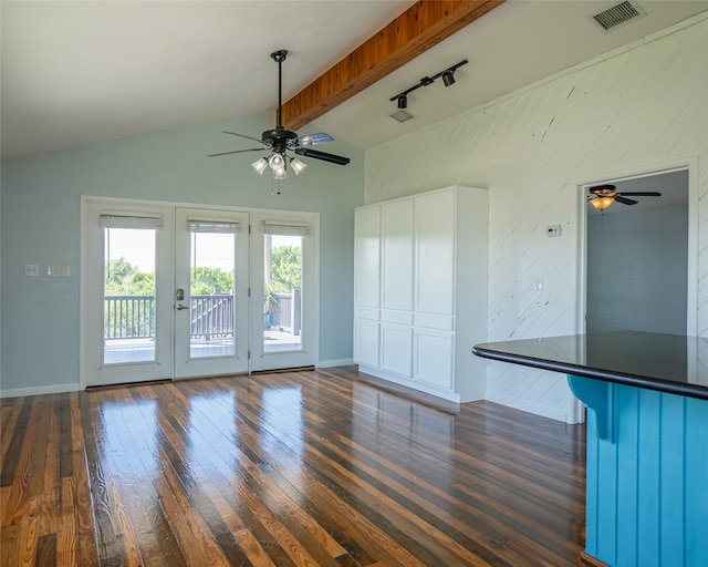 unfurnished living room featuring dark wood-type flooring, rail lighting, ceiling fan, and lofted ceiling with beams