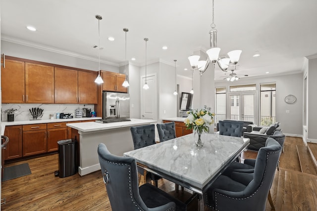 dining space with ceiling fan with notable chandelier, dark hardwood / wood-style flooring, and crown molding