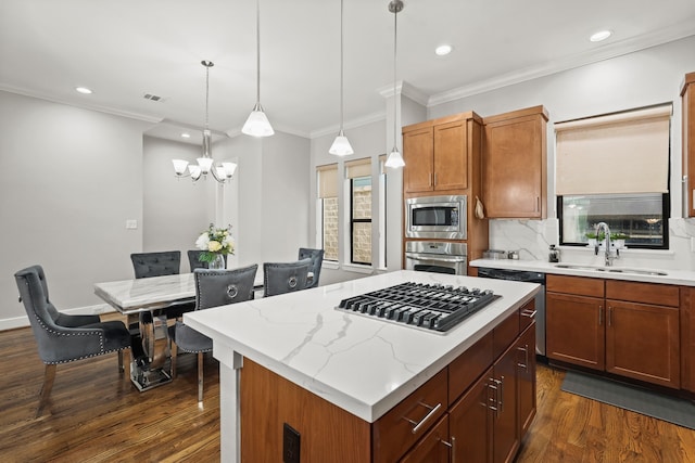 kitchen featuring dark hardwood / wood-style flooring, pendant lighting, appliances with stainless steel finishes, a center island, and sink