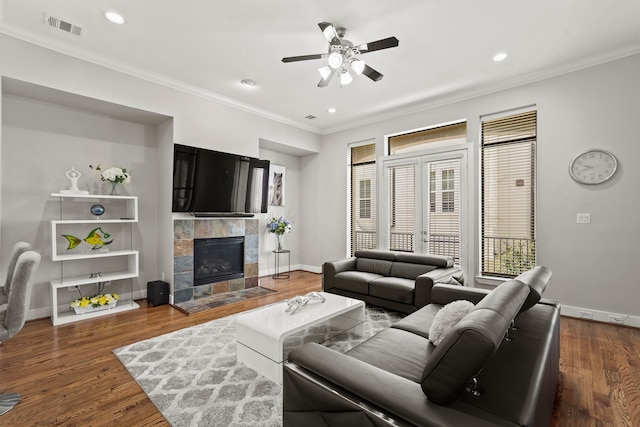 living room featuring ornamental molding, hardwood / wood-style flooring, ceiling fan, and a tile fireplace