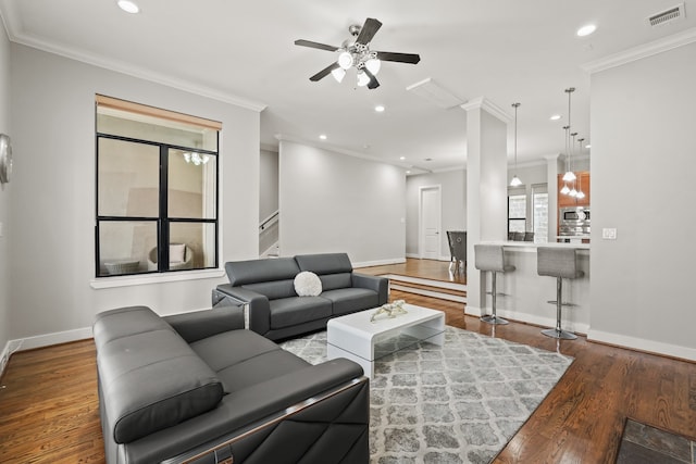 living room with decorative columns, ceiling fan, dark hardwood / wood-style flooring, and crown molding