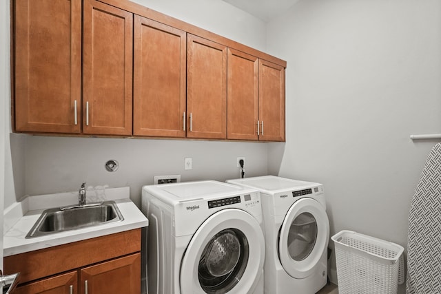 laundry room with washing machine and clothes dryer, cabinets, and sink