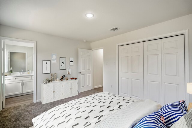 carpeted bedroom featuring a closet, connected bathroom, and sink