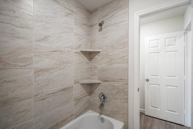 bathroom with hardwood / wood-style floors and tiled shower / bath