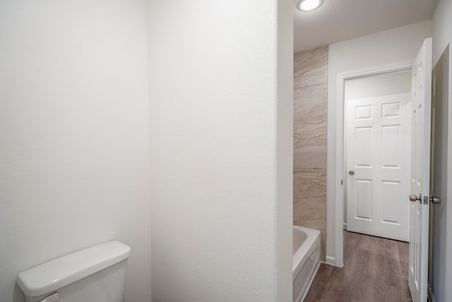 bathroom featuring a tub, hardwood / wood-style floors, and toilet