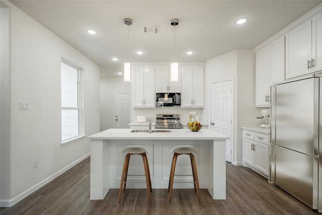 kitchen with dark hardwood / wood-style flooring, stainless steel appliances, and an island with sink