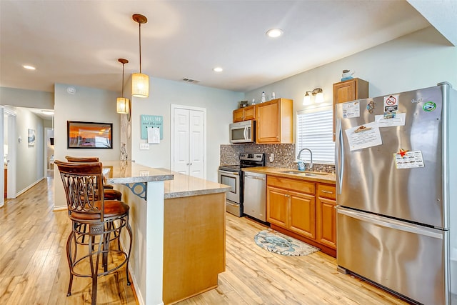 kitchen featuring a breakfast bar area, light hardwood / wood-style flooring, backsplash, stainless steel appliances, and sink