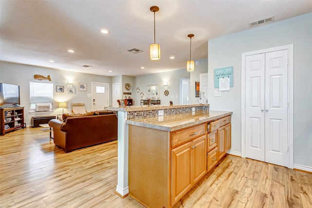 kitchen with pendant lighting, light wood-type flooring, and tasteful backsplash