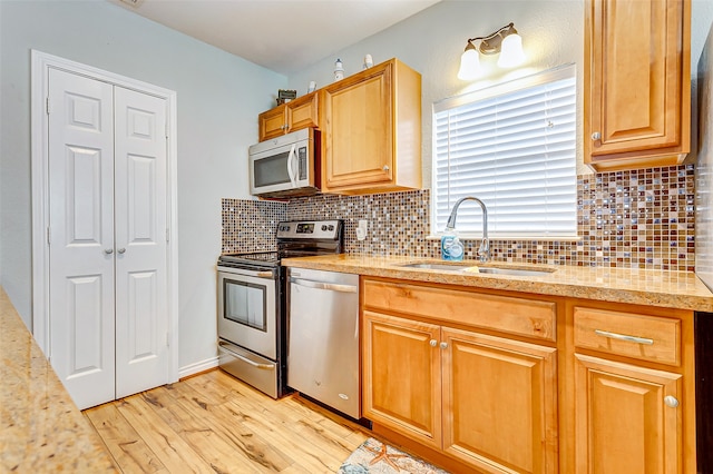 kitchen featuring stainless steel appliances, light hardwood / wood-style floors, tasteful backsplash, and sink