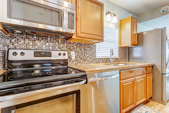 kitchen featuring appliances with stainless steel finishes, backsplash, sink, and light hardwood / wood-style floors