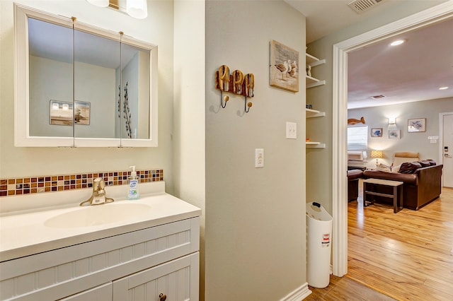 bathroom with hardwood / wood-style floors, decorative backsplash, and vanity