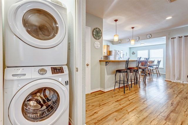 washroom featuring stacked washing maching and dryer and light hardwood / wood-style flooring