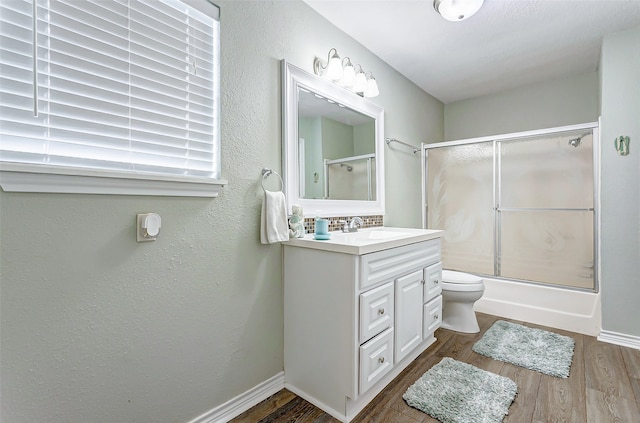 full bathroom with shower / bath combination with glass door, toilet, hardwood / wood-style flooring, and vanity