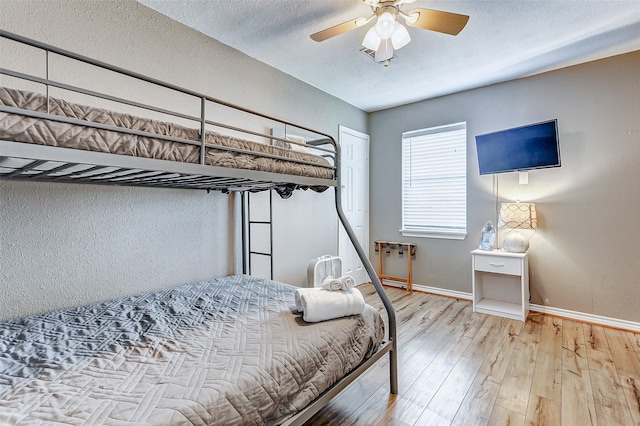 bedroom with light wood-type flooring, ceiling fan, and a textured ceiling