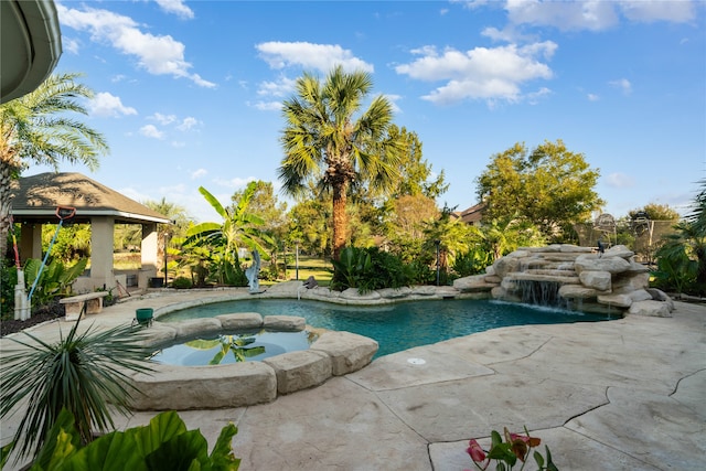 view of pool featuring a patio, pool water feature, and an in ground hot tub