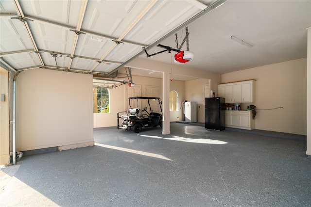 garage featuring a garage door opener, black refrigerator, and washing machine and clothes dryer