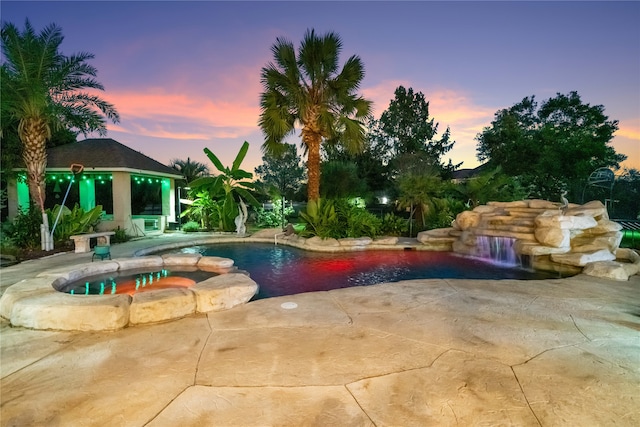 pool at dusk featuring a gazebo, an in ground hot tub, pool water feature, and a patio