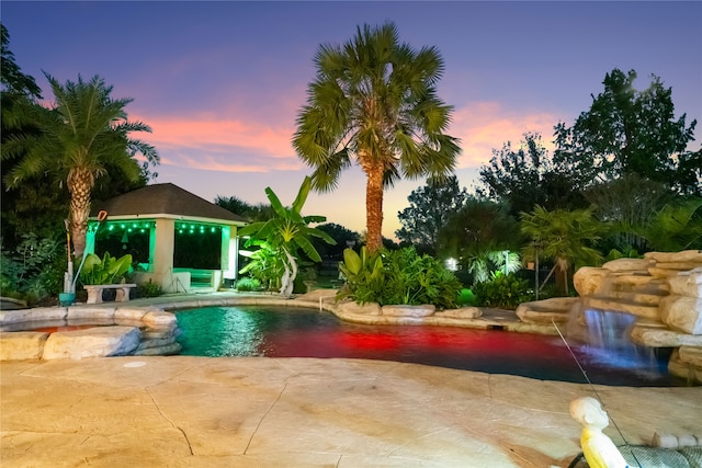 pool at dusk featuring a gazebo and a patio area