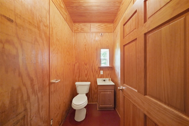 bathroom with vanity, toilet, wooden walls, and wood ceiling